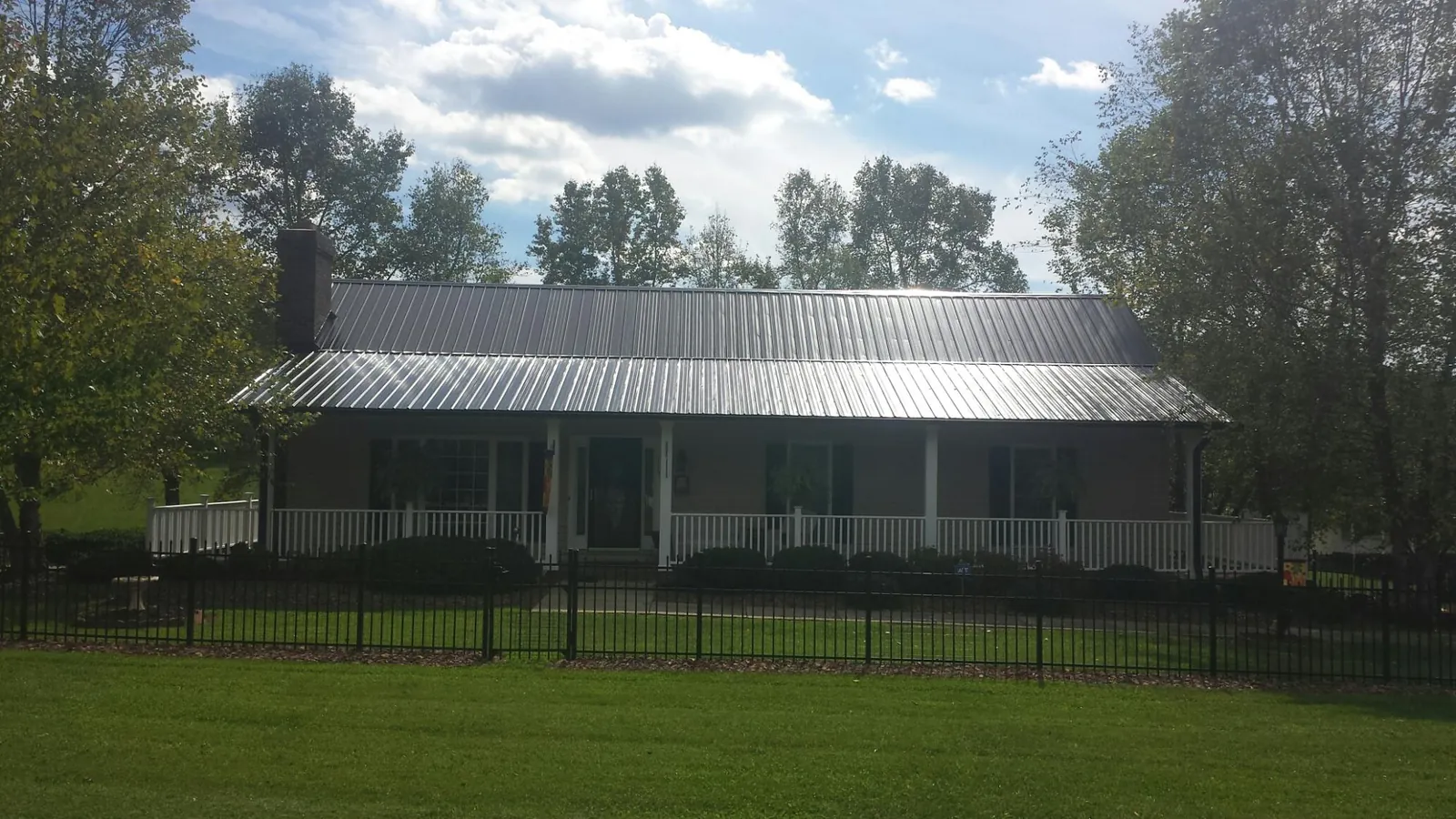 Gray metal roof on a brick ranch with a full width front porch — Gutter Guard Installation work by our crew in Gleason