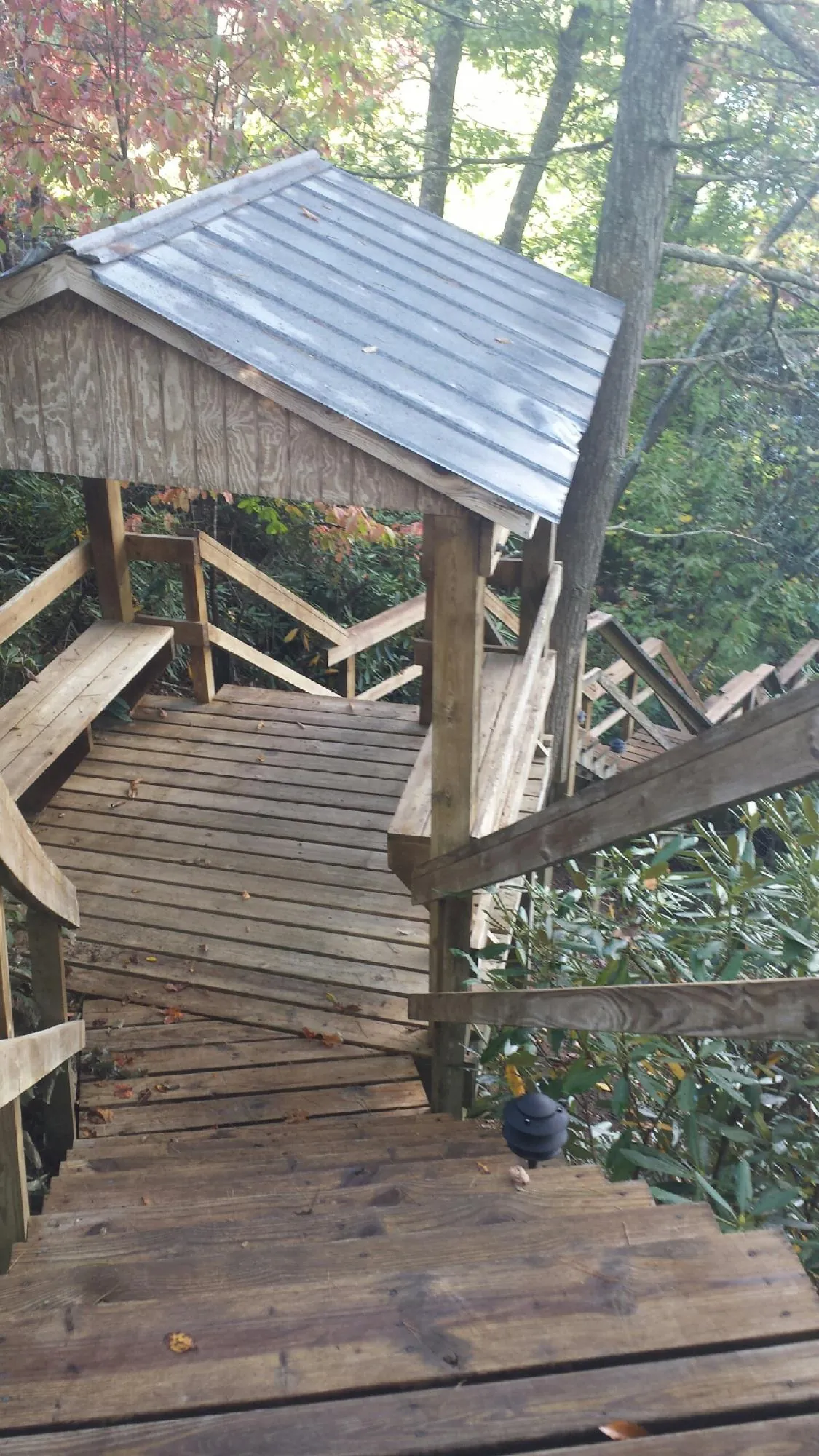 Metal roofed shelter over wooden steps on a wooded walkway — Skylight Repair & Installation work by our crew in Gleason