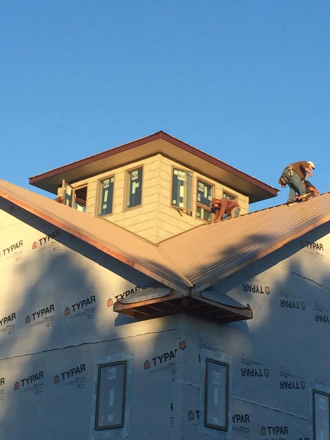 Roofers working around a rooftop cupola on a new metal roof at sunset — Roof Waterproofing in Gleason by Roofing Brothers